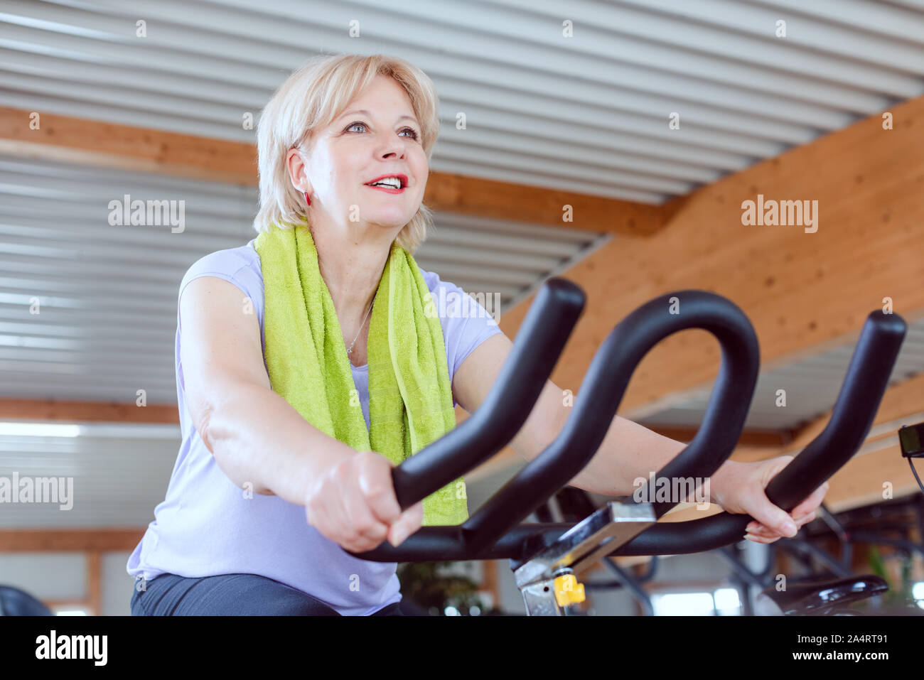 Senior donna sulla cyclette in palestra Foto Stock