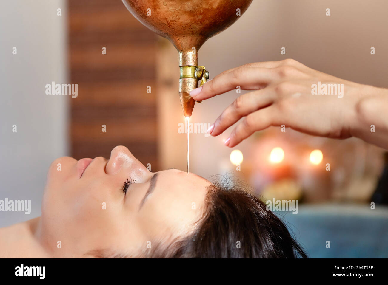 Massaggio ayurveda alternativa terapia di guarigione.bella femmina caucasica getting shirodhara trattamento giacente su di un tavolo di legno in India salon Foto Stock