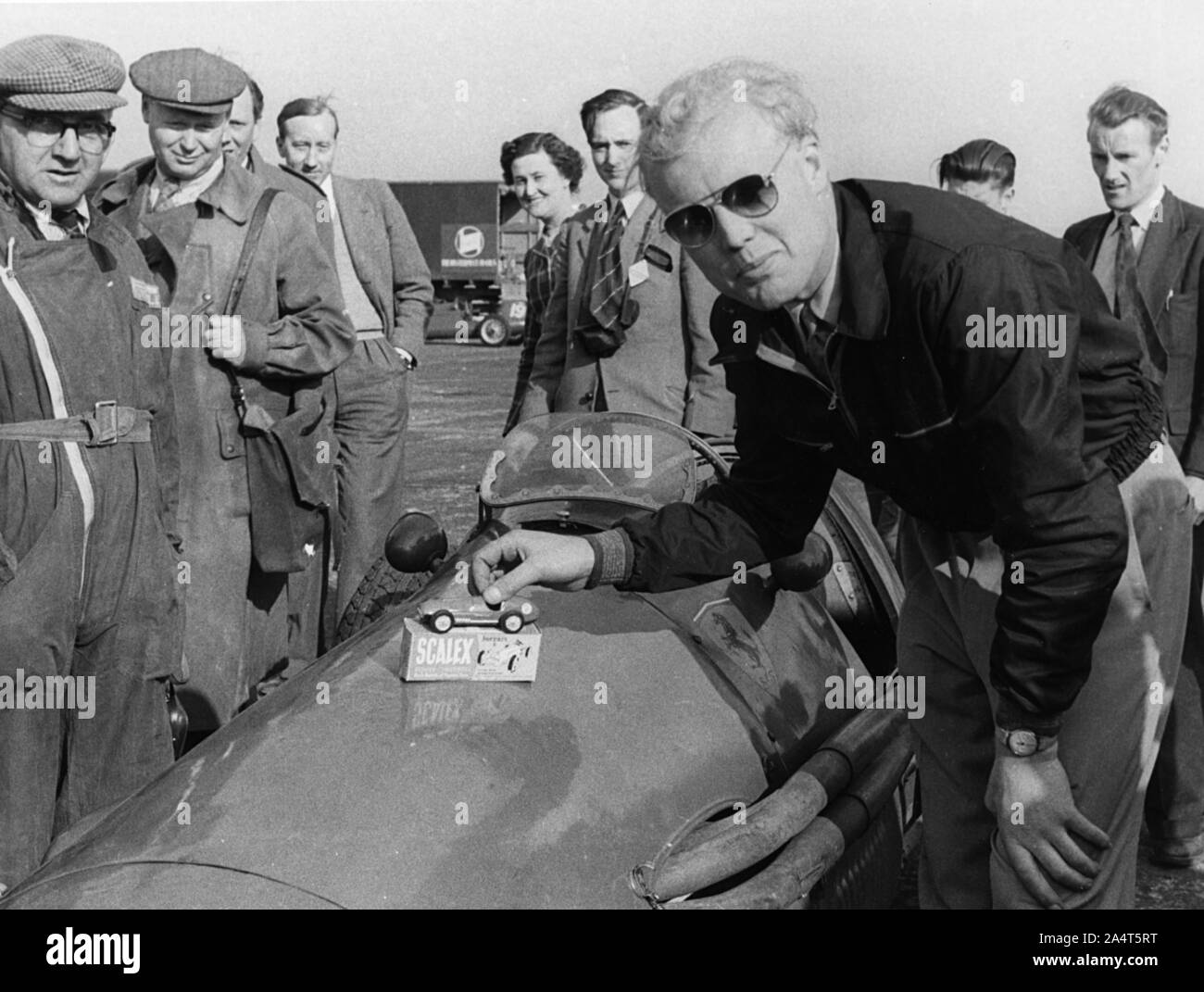 Mike Hawthorn ammirando un giocattolo modello Ferrari sulla sua Ferrari racing. Foto Stock