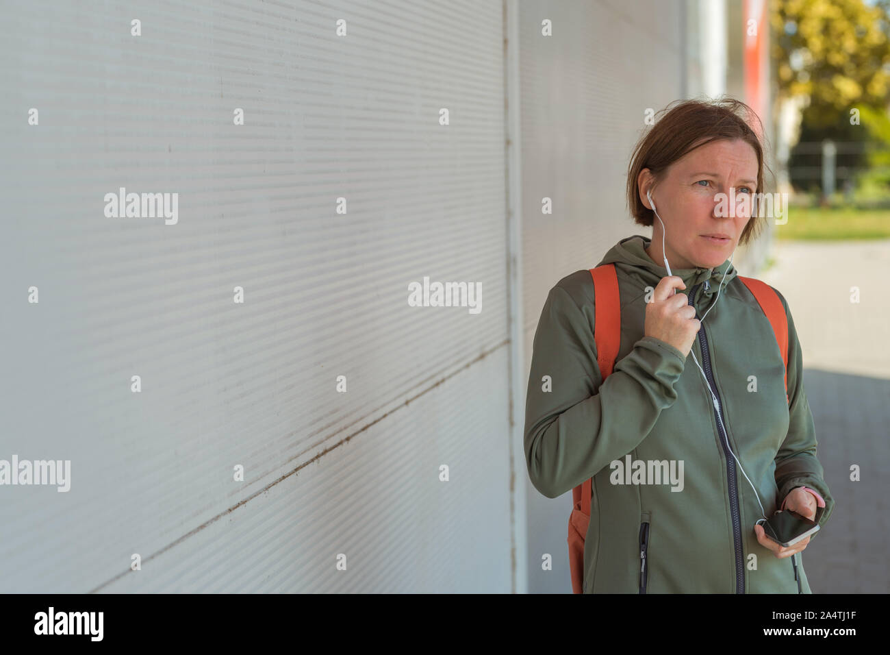 Pareggiatore femmina parlando al telefono cellulare in modalità vivavoce durante la camminata veloce la strada Foto Stock