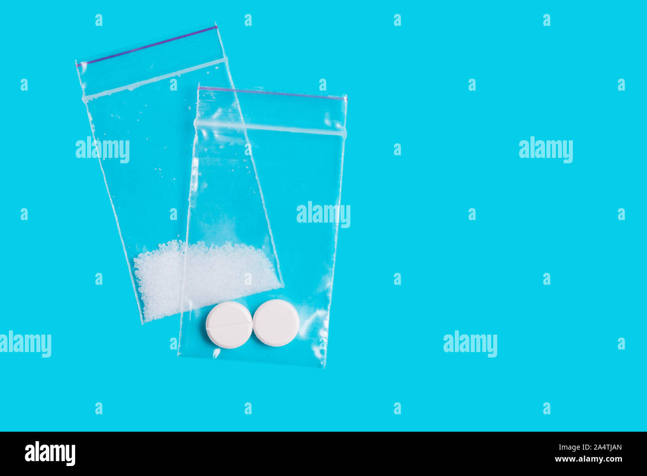 Le droghe sintetiche, pillole, ecstasy in bustine su sfondo blu Foto Stock