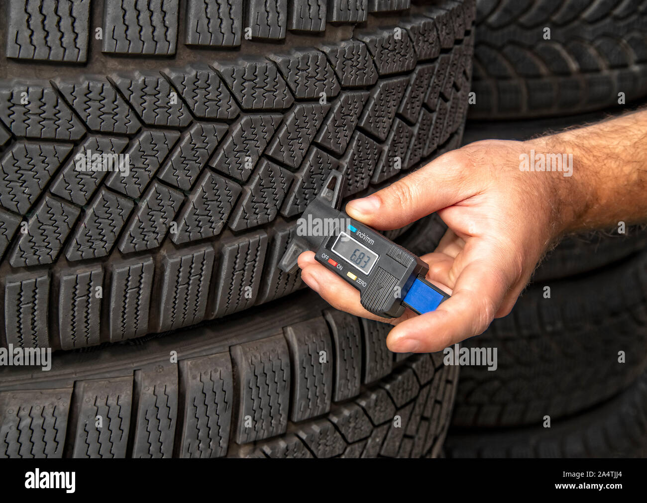 Misurare la profondità del battistrada di un pneumatico con uno strumento di misura digitale Foto Stock