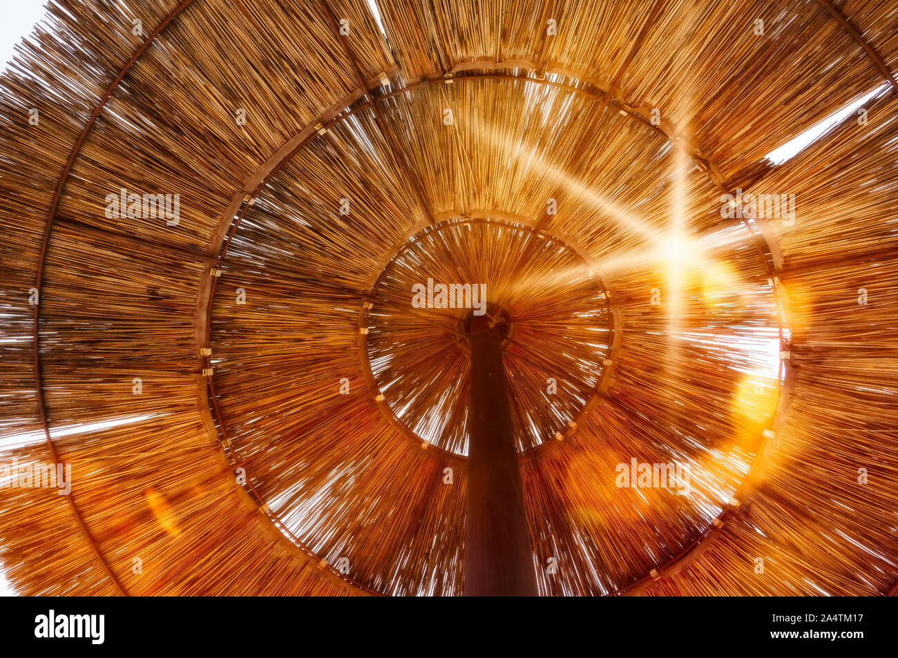 Vista dal basso attraverso un ombrellone di paglia al sole Foto Stock