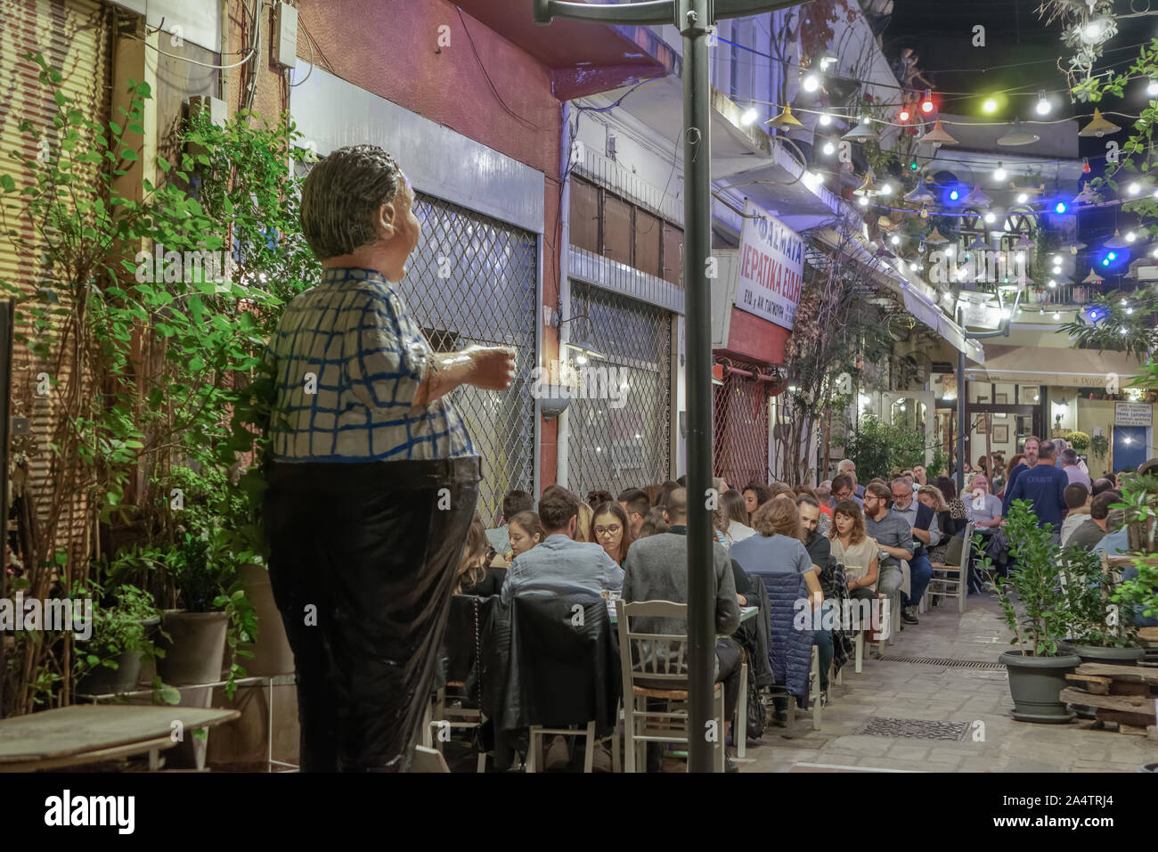 Hellenic scena notturna di persone alla taverna all'aperto ristoranti. La folla non identificato Mangiare & bere a taverne in zona Bezesteni Salonicco. Foto Stock