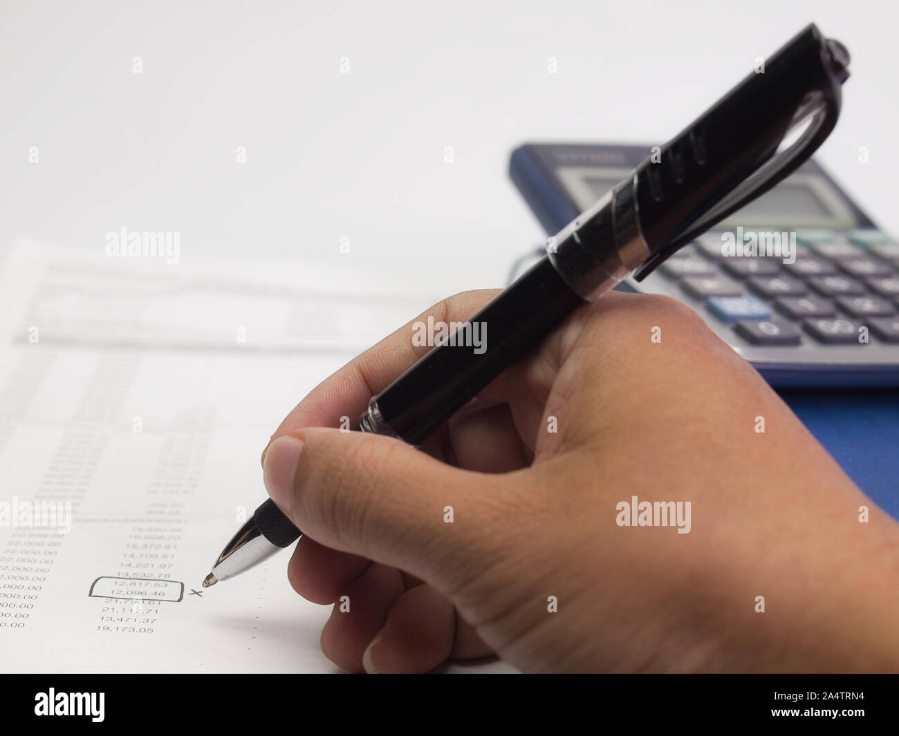 Fattura con Calcolatrice , e la mano di un uomo con una penna sulla scrivania. Foto Stock
