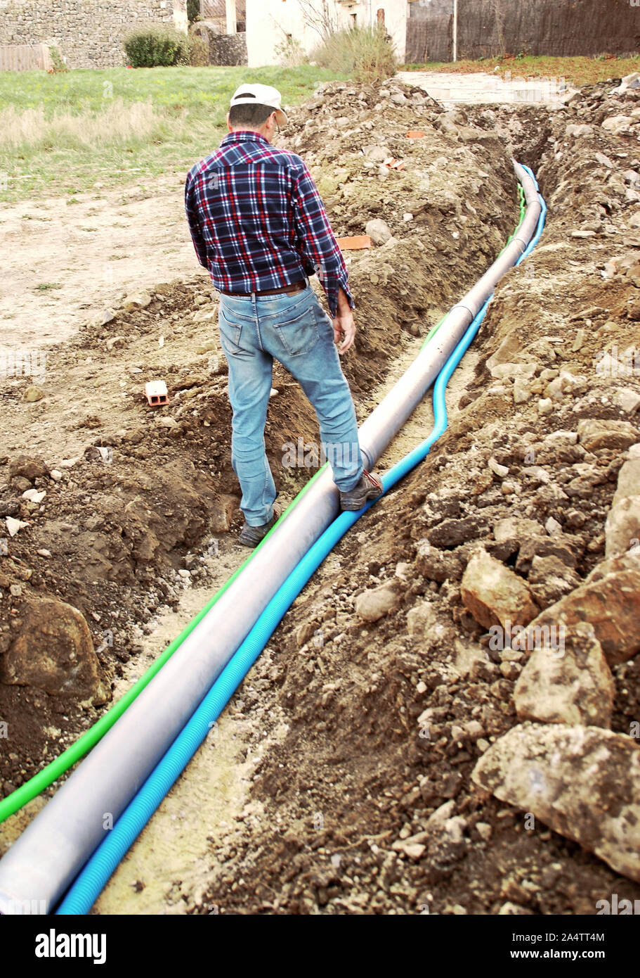 La posa di varie connessioni in una trincea di casa. Foto Stock