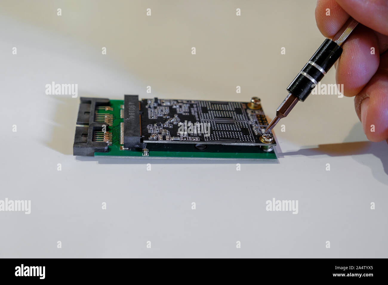 Mano umana lavorando su chipset ssd sostituire i componenti del computer con un cacciavite Foto Stock