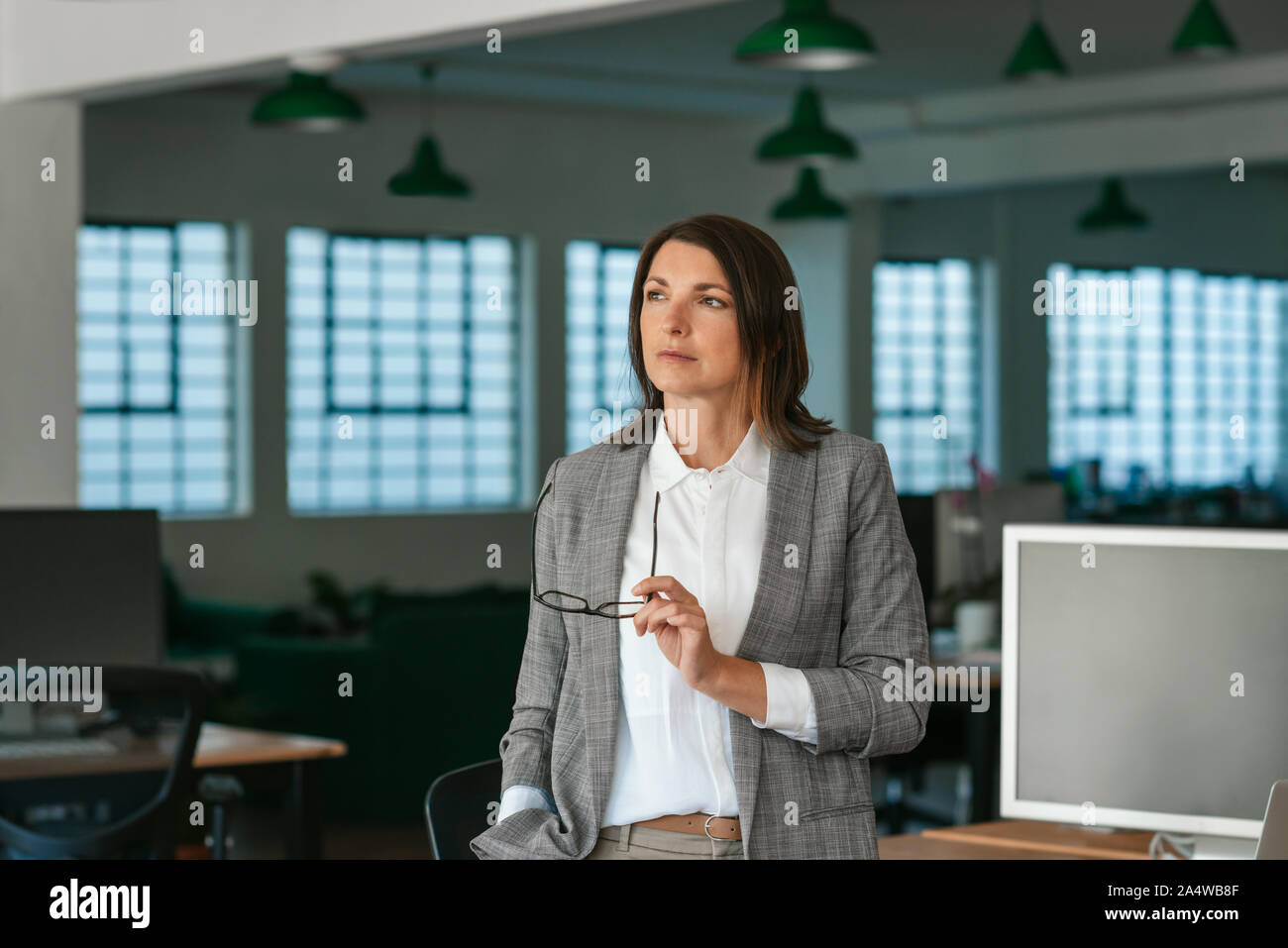 Imprenditrice in piedi in un ufficio a guardare in profondità nel pensiero Foto Stock