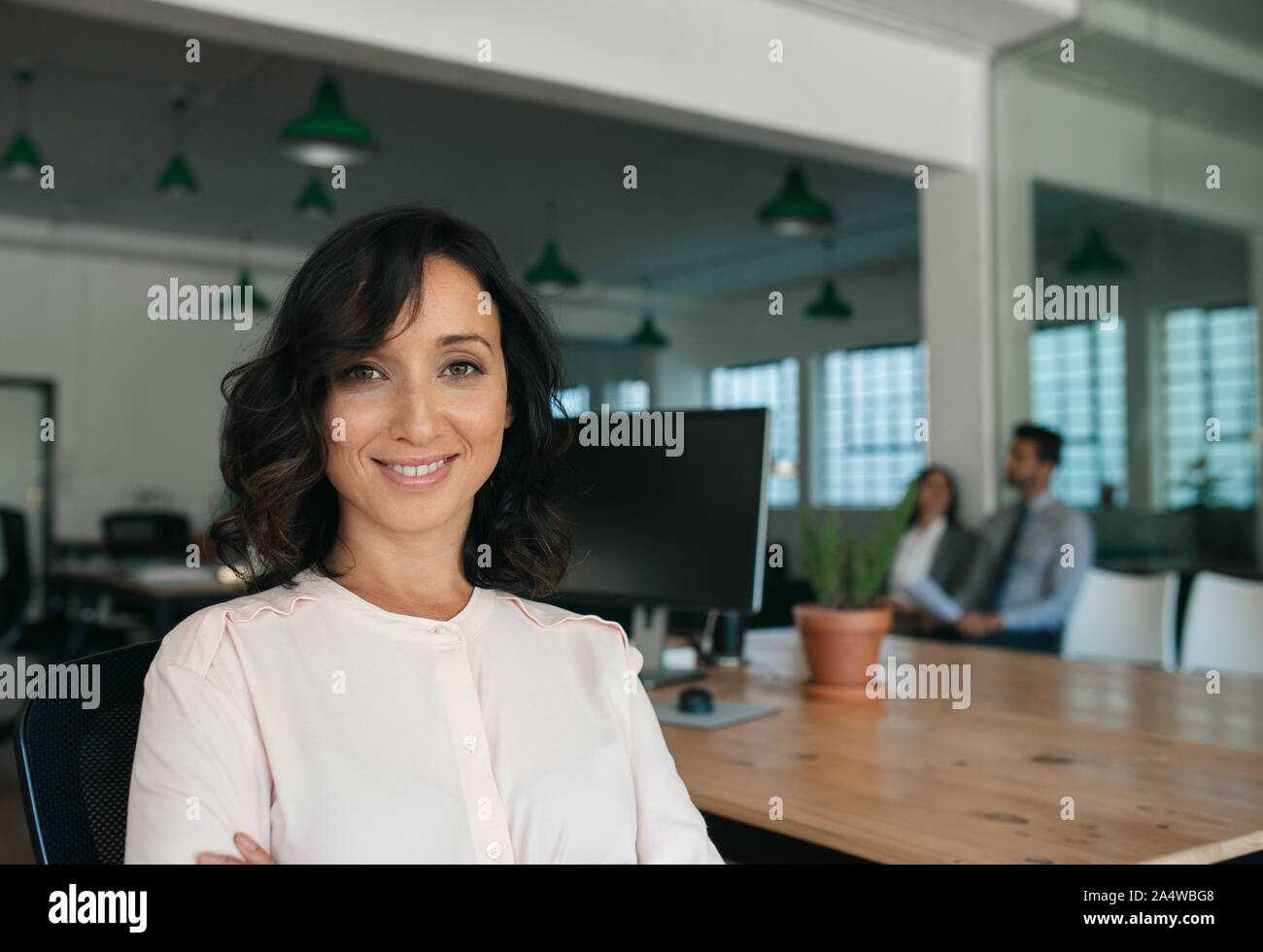 Sorridente giovane imprenditrice seduti a un tavolo in un ufficio Foto Stock