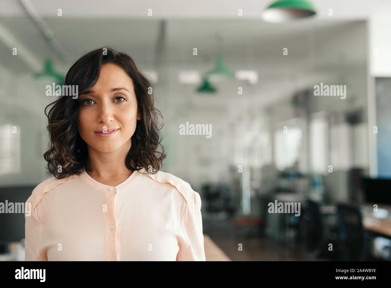 Sorridente giovane imprenditrice in piedi da solo in un ufficio di grandi dimensioni Foto Stock