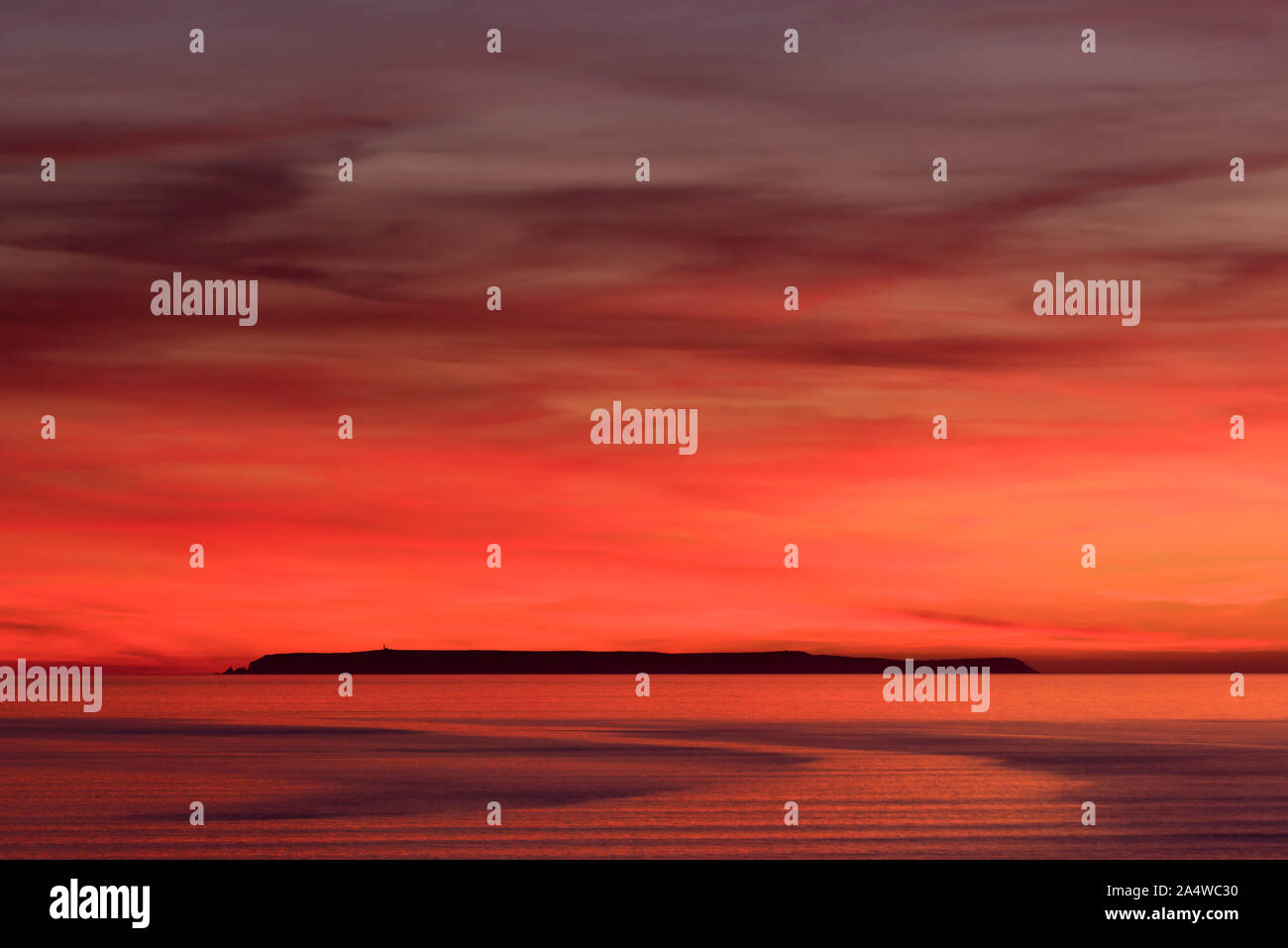 Un drammatico cielo rosso alla fine di una metà estate tramonto su Lundy Island nell'Oceano Atlantico visto da Condino In North Devon, in Inghilterra. Foto Stock