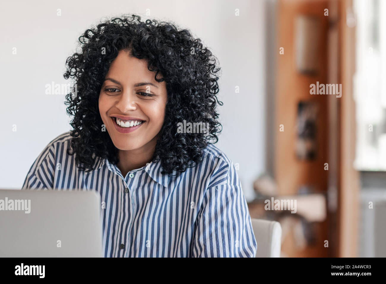 Ridendo femmina giovane imprenditore lavora da casa su un computer portatile Foto Stock