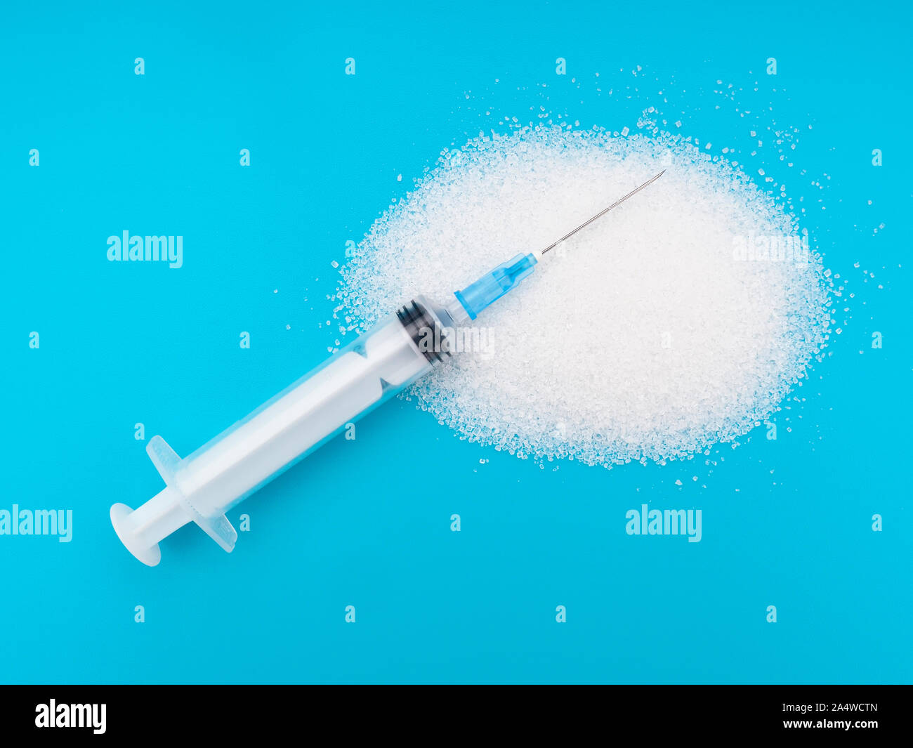 Lo zucchero cristallizzato bianco brillante su sfondo colorato con la siringa. Mangiare malsano, diabete i rischi per la salute ecc. Foto Stock