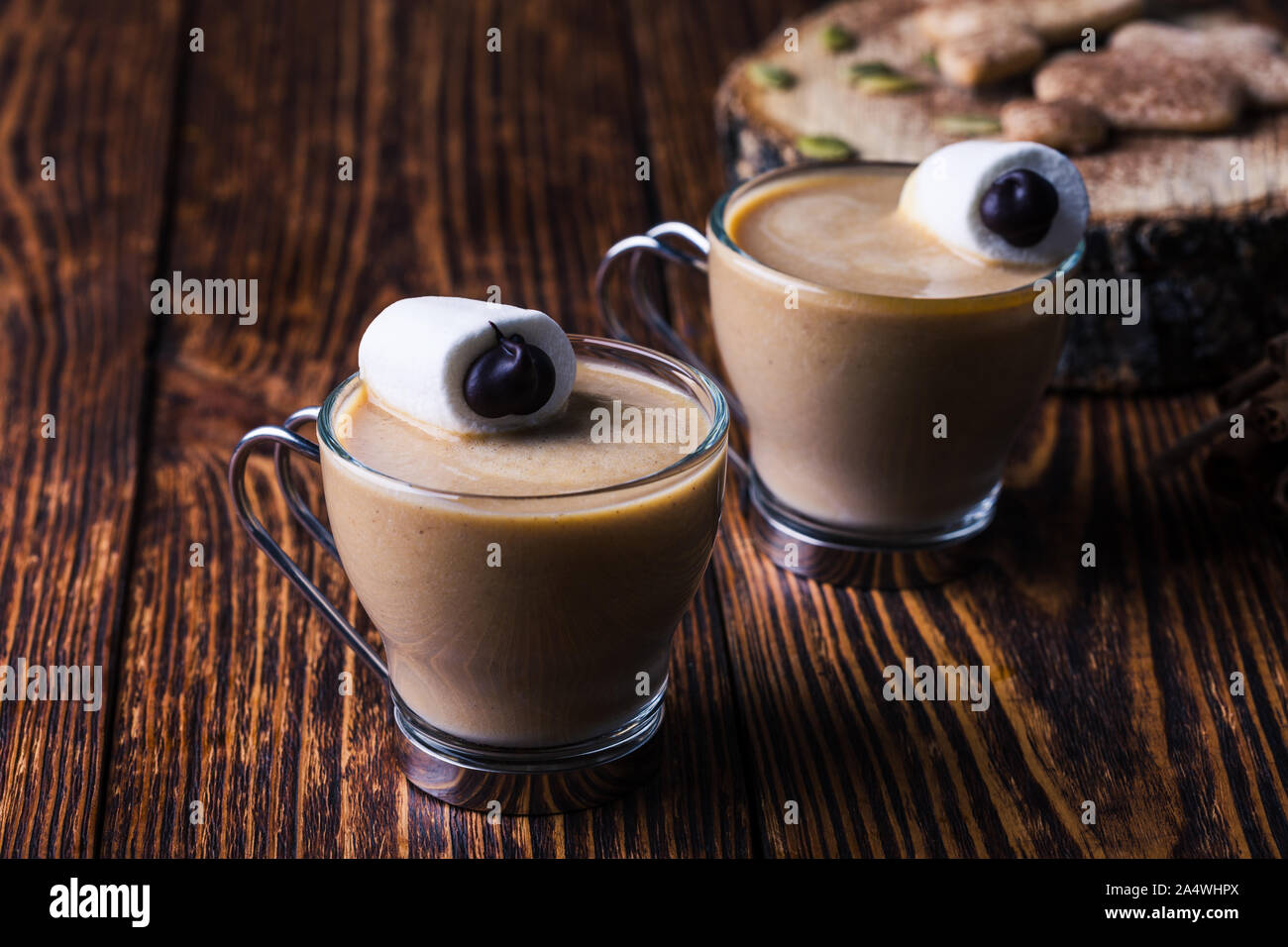 Happy monster, pumpkin spice latte con panna montata e grandi occhi marshmallow sulla parte superiore, Halloween dessert, marshmallow faccina sorridente sul rustico scheda di legno Foto Stock