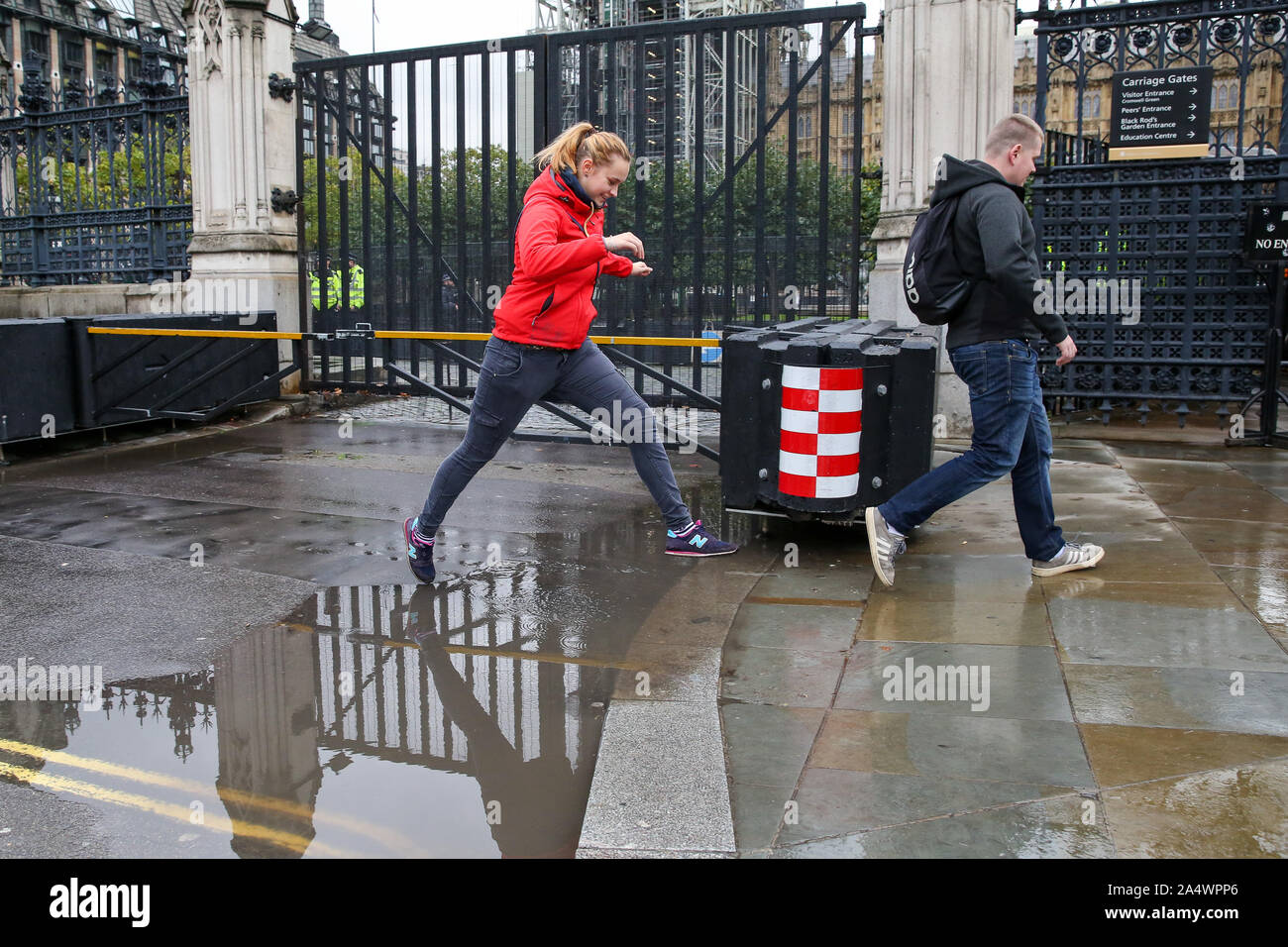 Londra, Regno Unito. Xvi Sep, 2018. Una donna salta sopra una pozza d'acqua di pioggia durante la notte seguente le precipitazioni alle porte delle case del parlamento di Westminster. Più è prevista pioggia nei prossimi giorni. Credito: Steve Taylor/SOPA Immagini/ZUMA filo/Alamy Live News Foto Stock