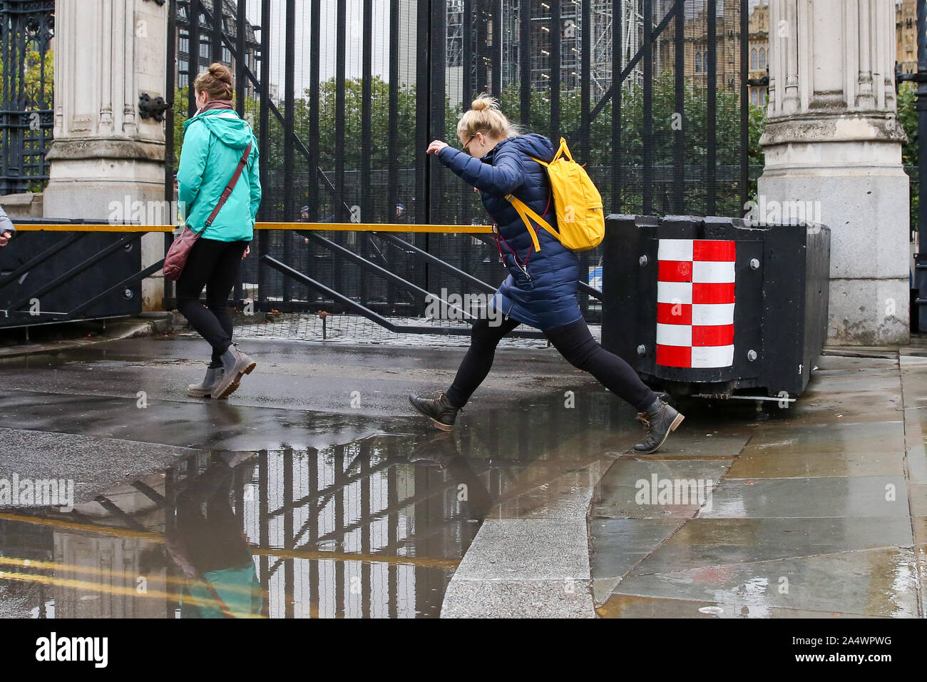 Londra, Regno Unito. Xvi Sep, 2018. Una donna salta sopra una pozza d'acqua di pioggia durante la notte seguente le precipitazioni alle porte delle case del parlamento di Westminster. Più è prevista pioggia nei prossimi giorni. Credito: Steve Taylor/SOPA Immagini/ZUMA filo/Alamy Live News Foto Stock