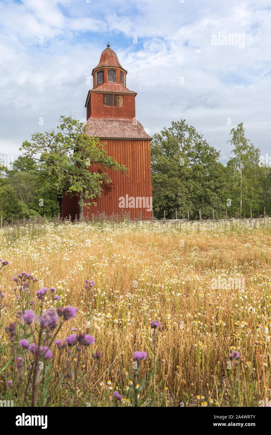 Svedese di paesaggio di campagna con una vecchia chiesa in legno. La chiesa in legno dipinto in tradizionali falu svedese di colore rosso e non c'è erba secca e fl Foto Stock