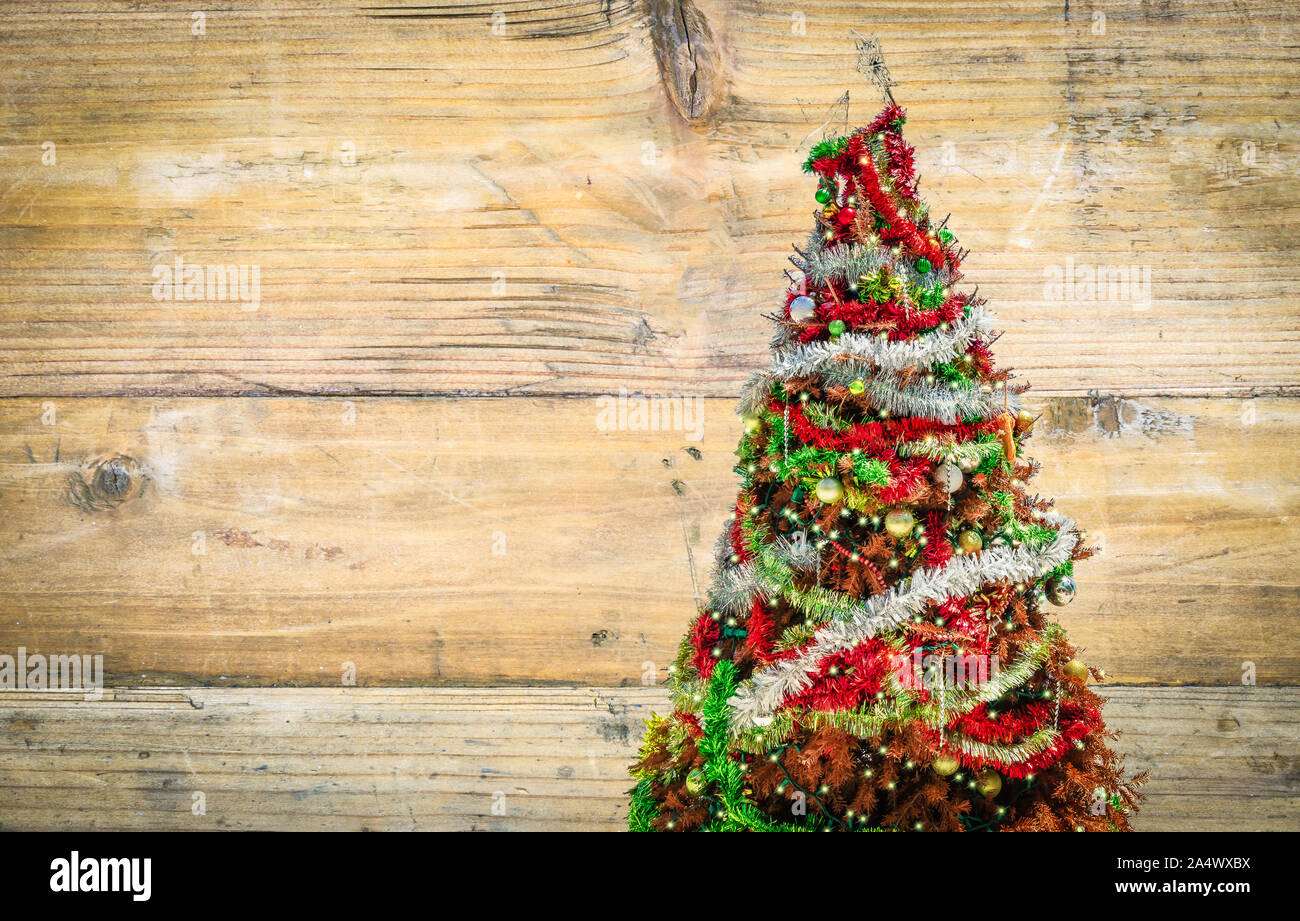 Vista laterale del vecchio albero di Natale con decorazioni su sfondo di legno. Biglietto di auguri o poster sfondo. Foto Stock