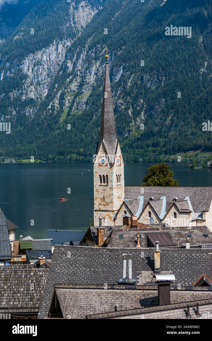 Il campanile della chiesa di Hallstatt con il lago e le montagne sullo sfondo Foto Stock