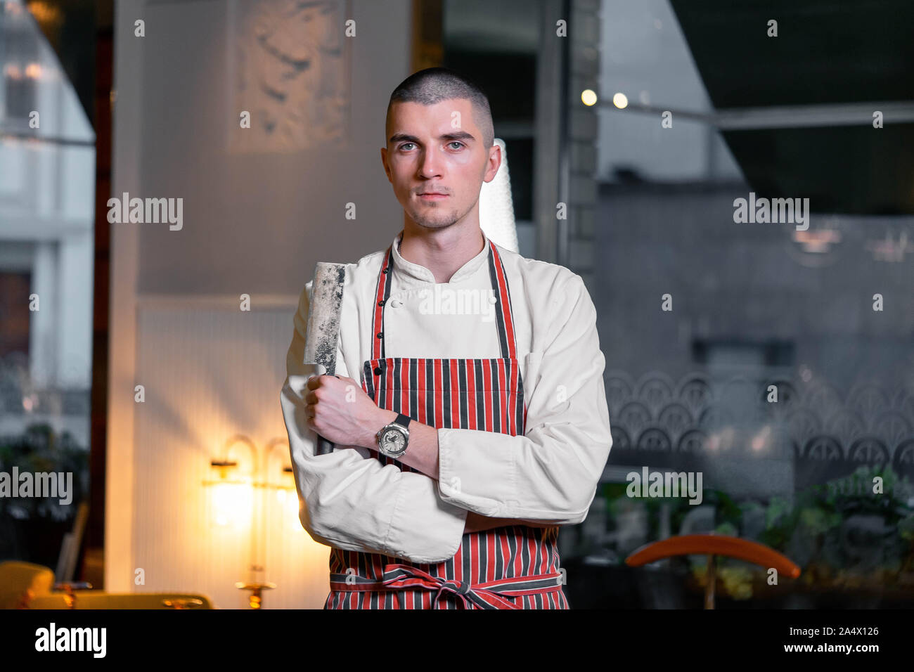 Giovane bello brutale cuoco capo azienda coltello nel moderno ristorante interno. Foto Stock