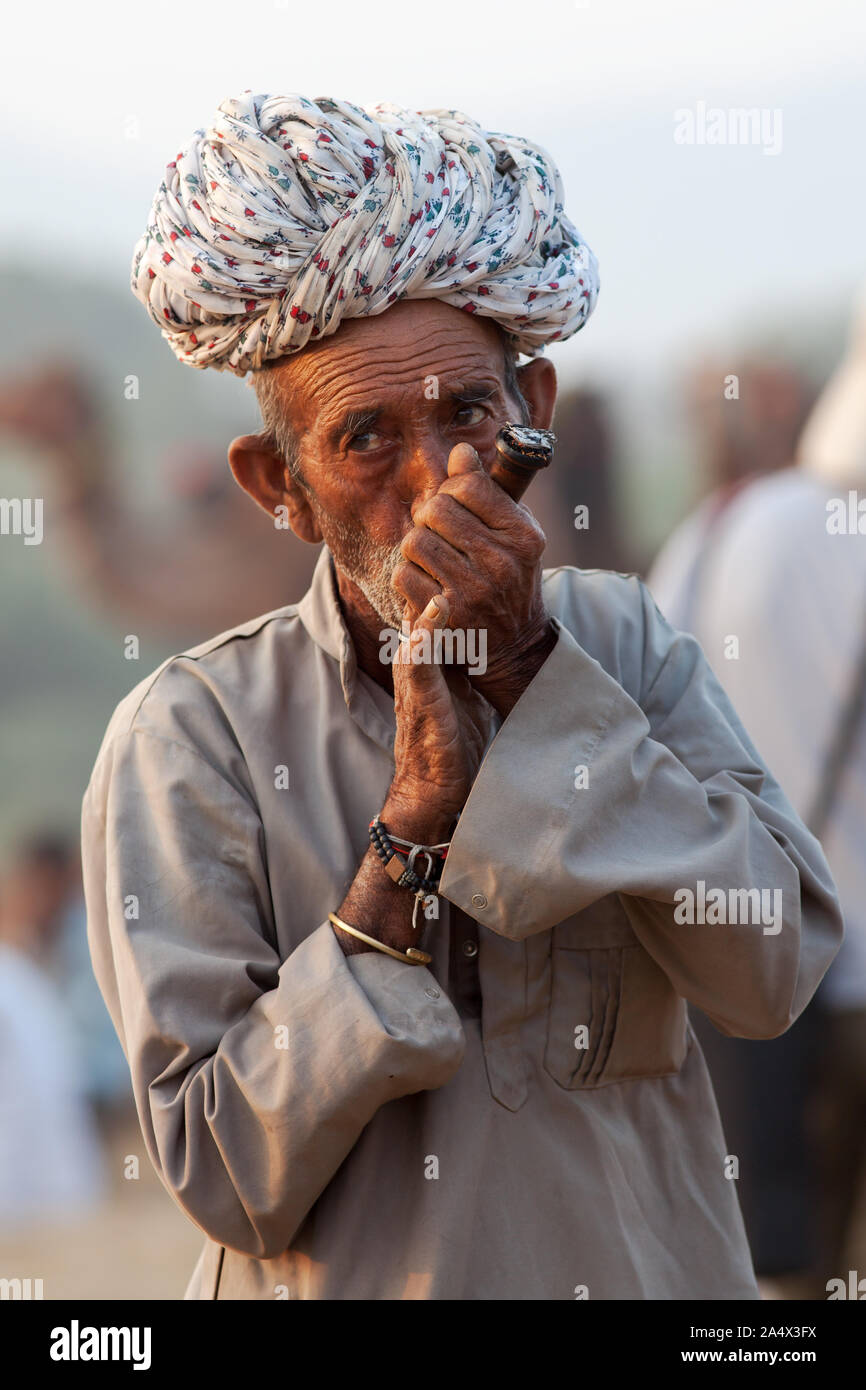 Uomo di Rajasthani fumare una chillum (tubo) di hashish a Pushkar Camel Fair, Rajasthan, India Foto Stock