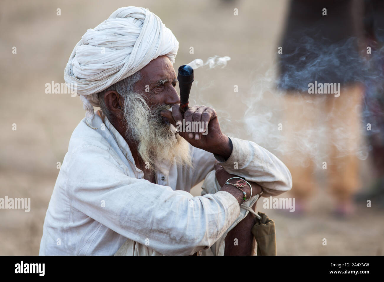 Uomo di Rajasthani fumare una chillum (tubo) di hashish a Pushkar Camel Fair, Rajasthan, India Foto Stock