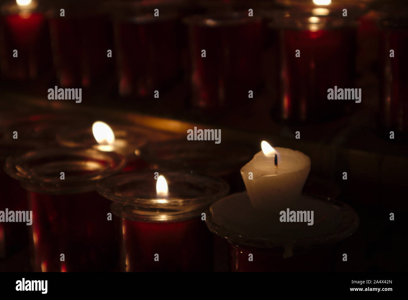 Candele accese in un luogo per fare offerte di religiosi in un angolo della chiesa Foto Stock