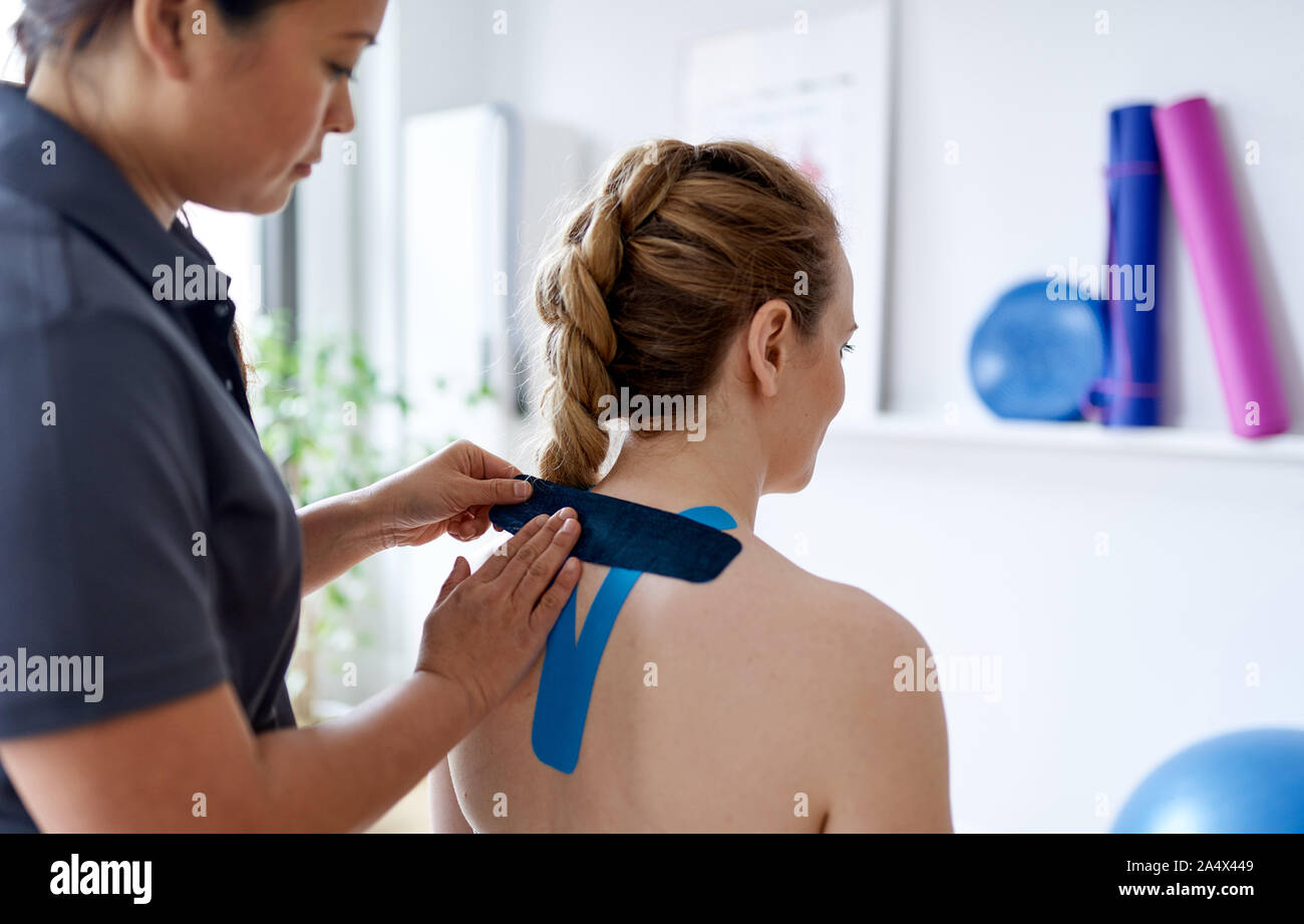 Donna cinese massaggi terapista kinesio applicando del nastro per la sho Foto Stock