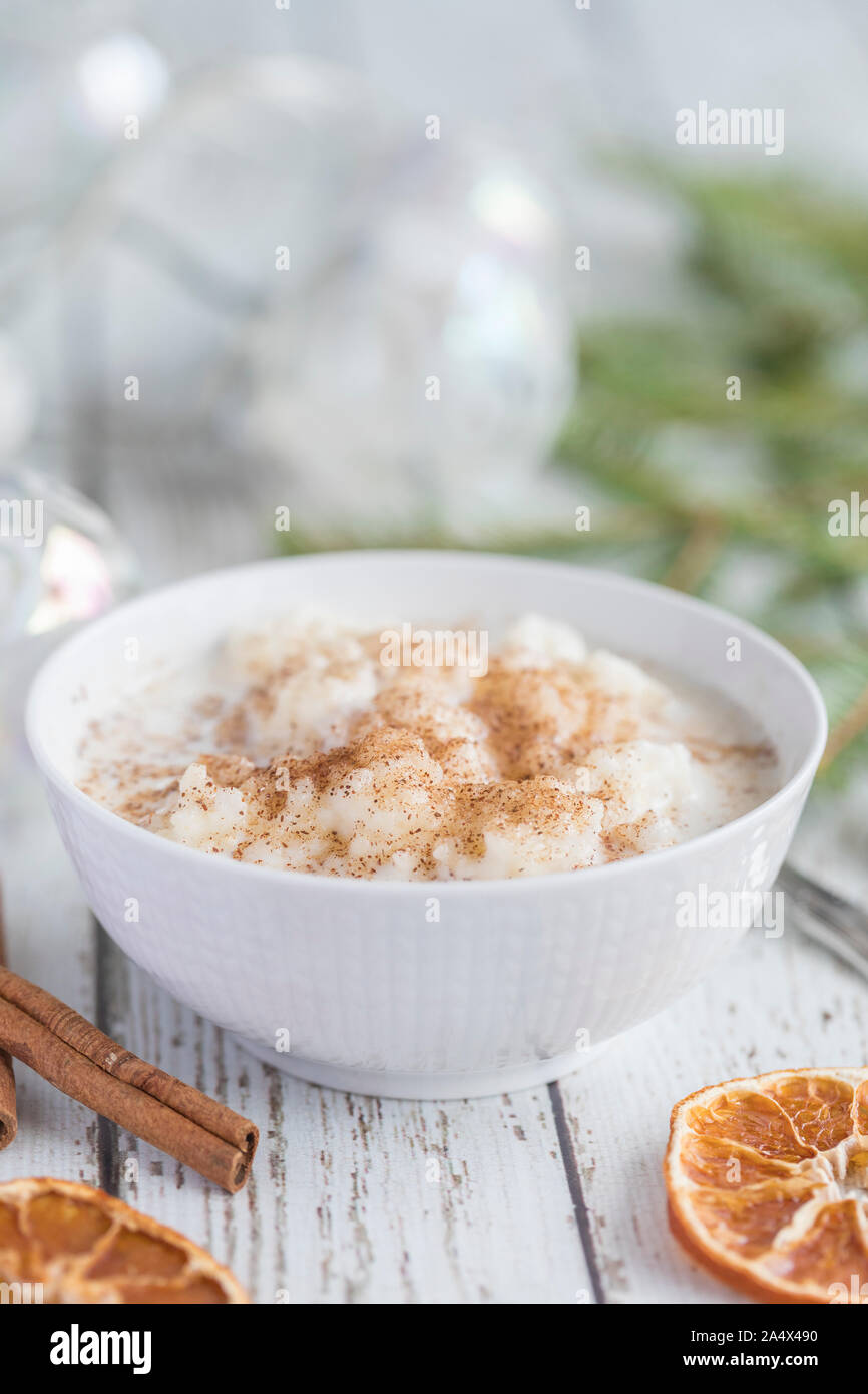 Close up tradizionale budino di riso noto anche come tomtegröt o risgrynsgröt svedese. Il budino di riso è in un colore bianco porcellana ciotola su di un legno bianco Foto Stock