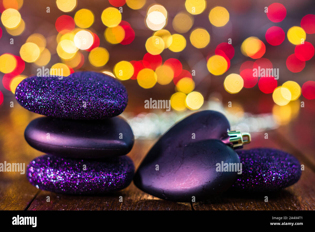 Le decorazioni di Natale contro sfondo sfocato e fuori fuoco luci. Glittery a forma di cuore palle di Natale Foto Stock