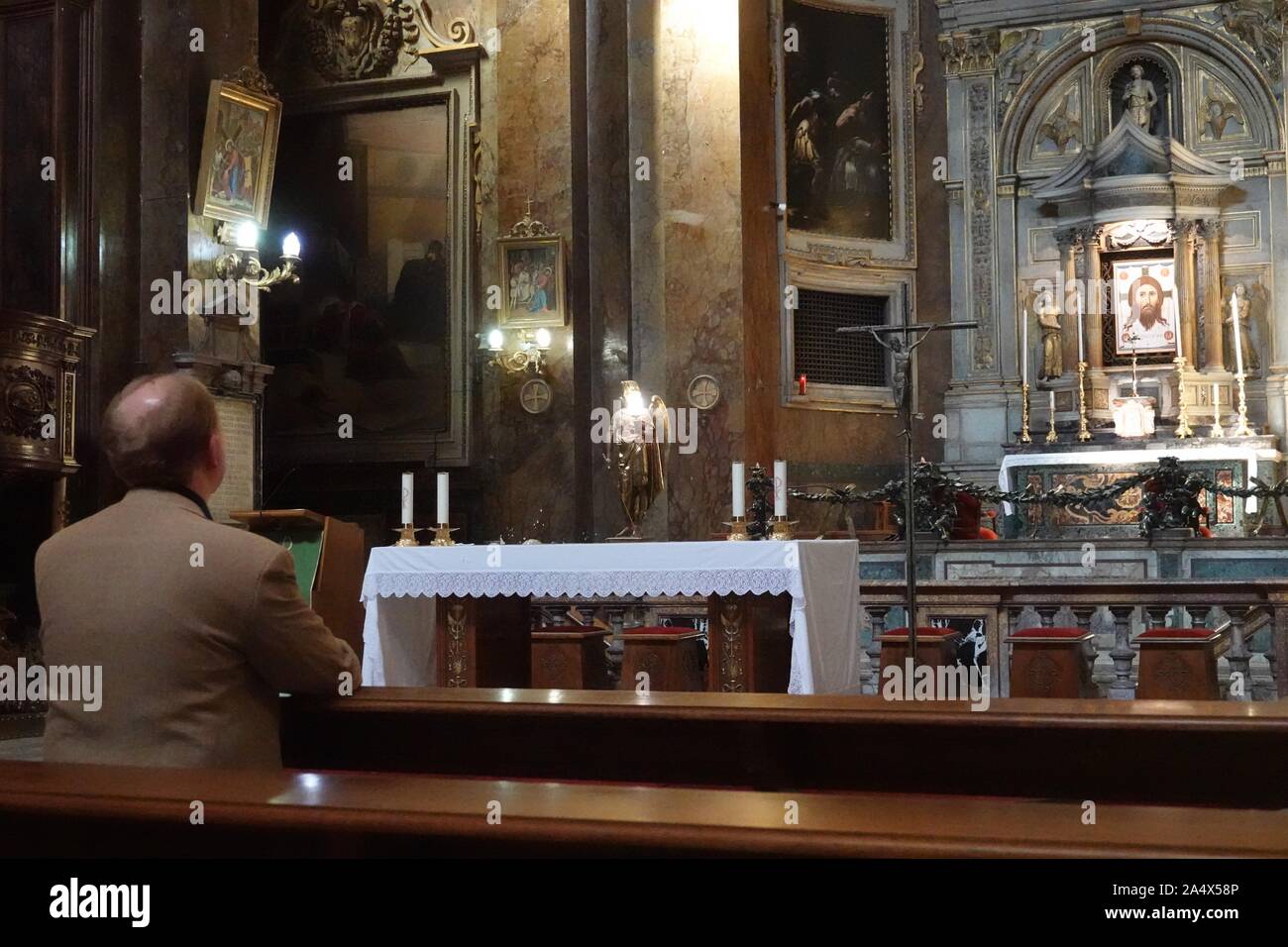Un uomo che prega in San Silvestro la Chiesa che è in Roma, Italia Foto Stock