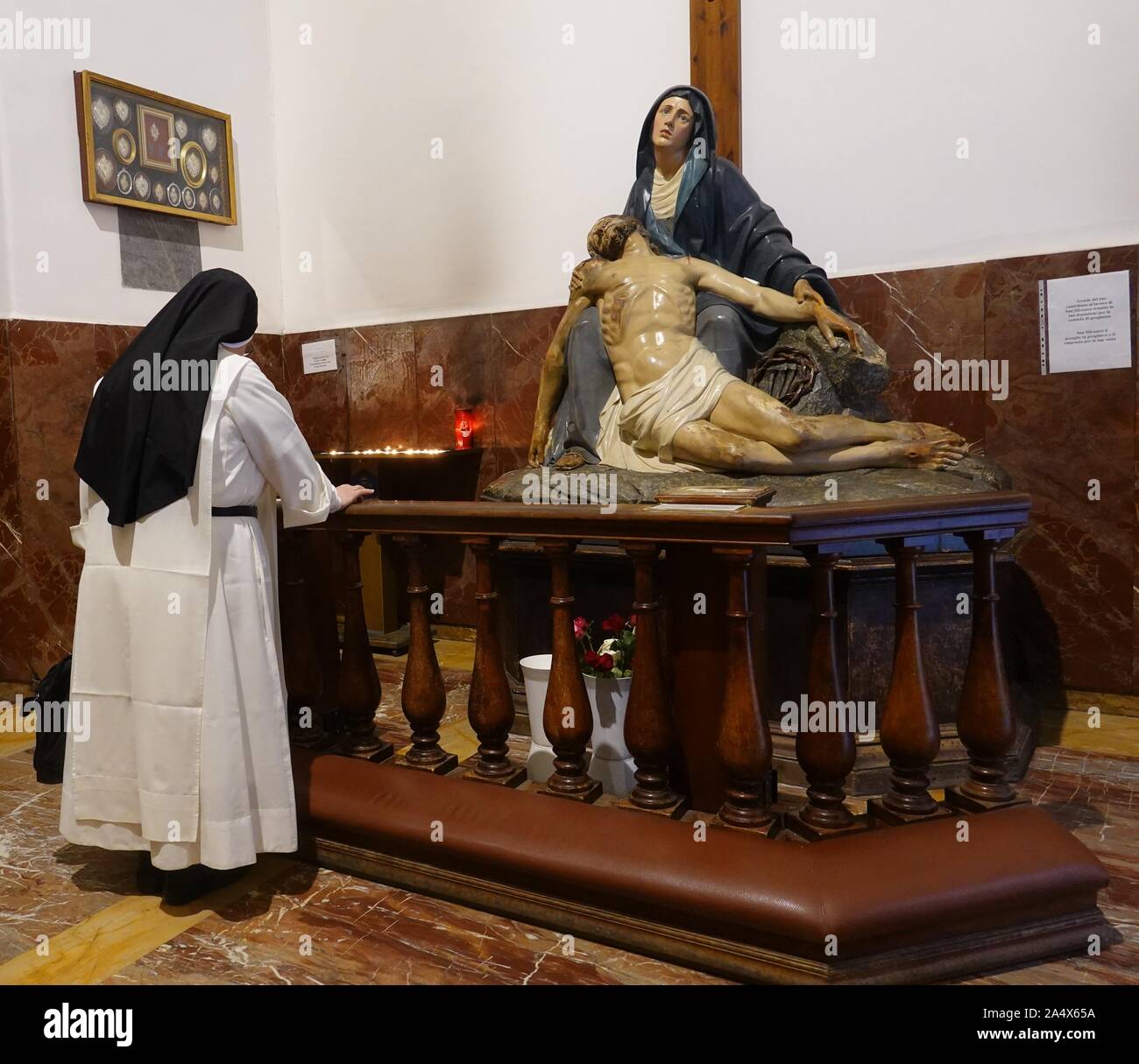 Una suora che prega in una statua di San Silvestro chiesa in Roma, Italia Foto Stock