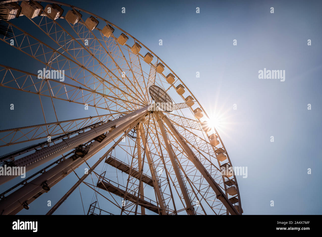 Ampia angolazione del grande ruota panoramica Ferris contro il cielo blu con sunburst Foto Stock