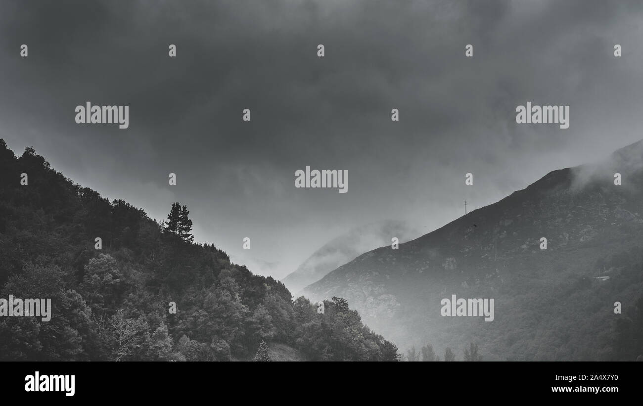 La nebbia nella valle tra le montagne, toni scuri e bianco nebbia, moody stile, Asturias, Spagna. Foto Stock