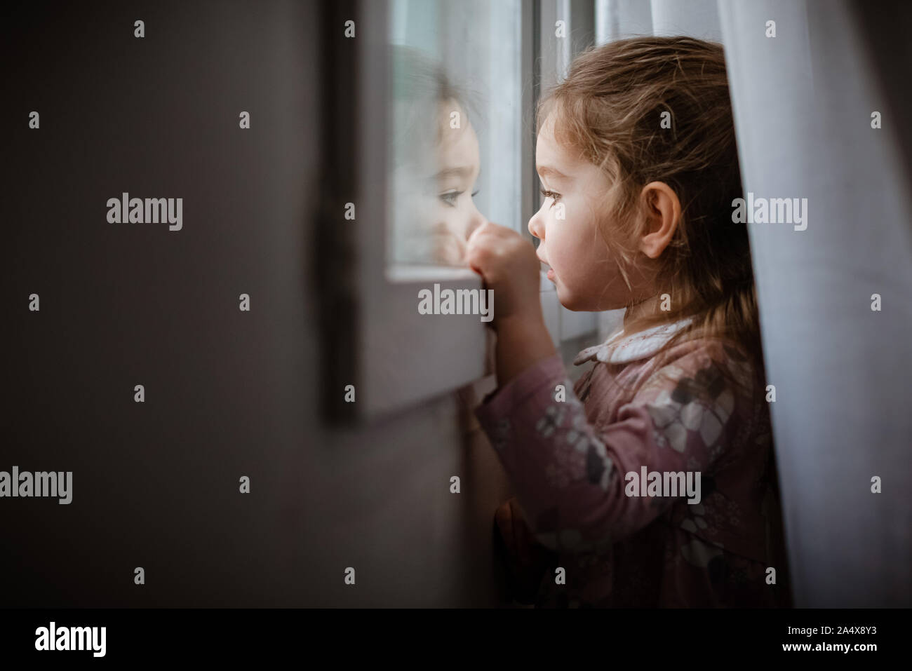 Vista laterale del giovane ragazza guardando fuori dalla finestra a pioggia Foto Stock