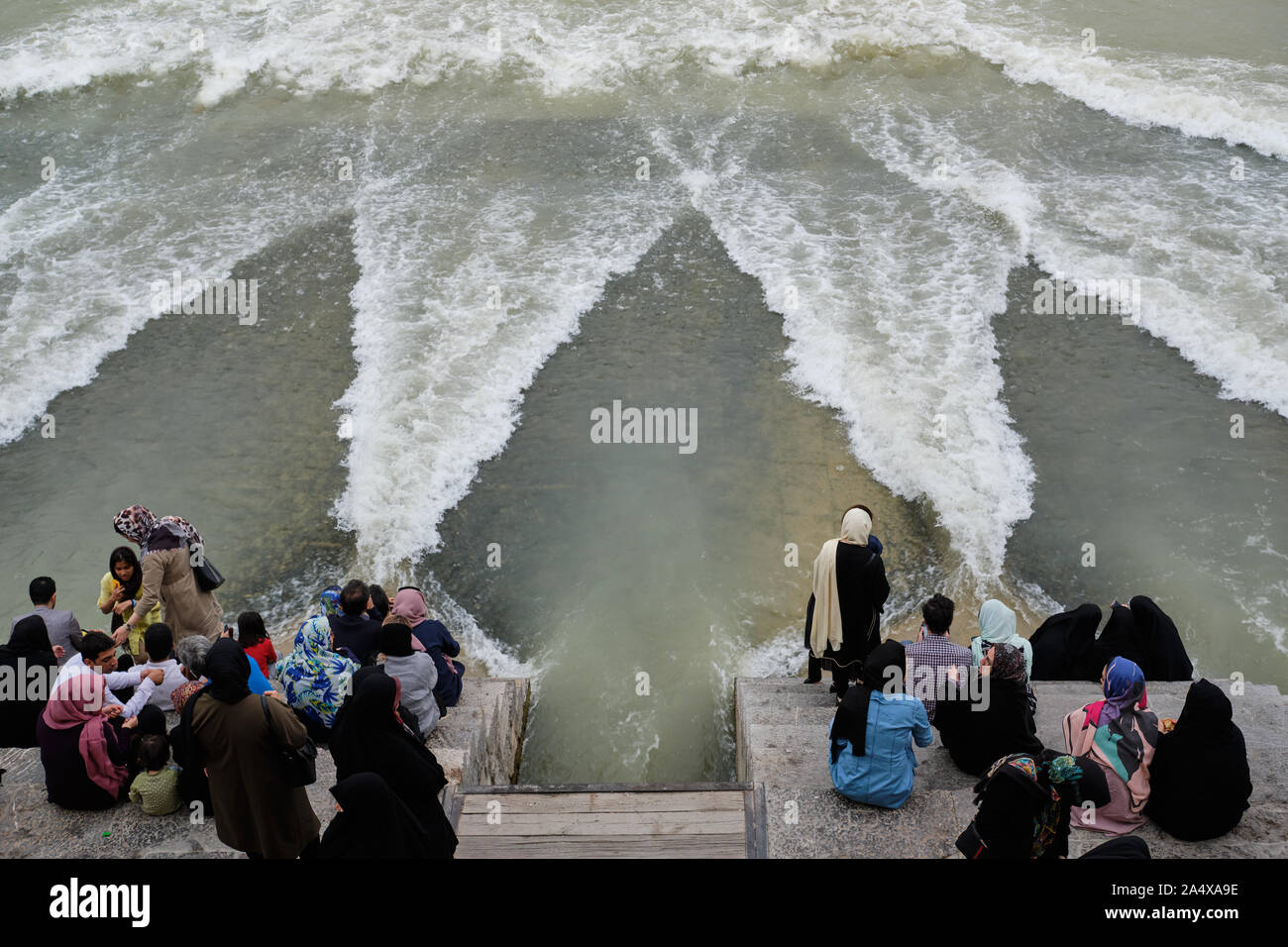 Isfahan, Iran - 1 Maggio 2019: Gente seduta sul ponte Khaju guardando l'evento inconsueto di acqua che scorre sotto il ponte Foto Stock