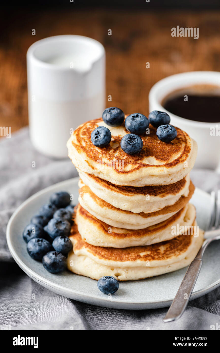 La colazione pancake con mirtilli e tazza di caffè sul tavolo di legno, con orientamento verticale Foto Stock