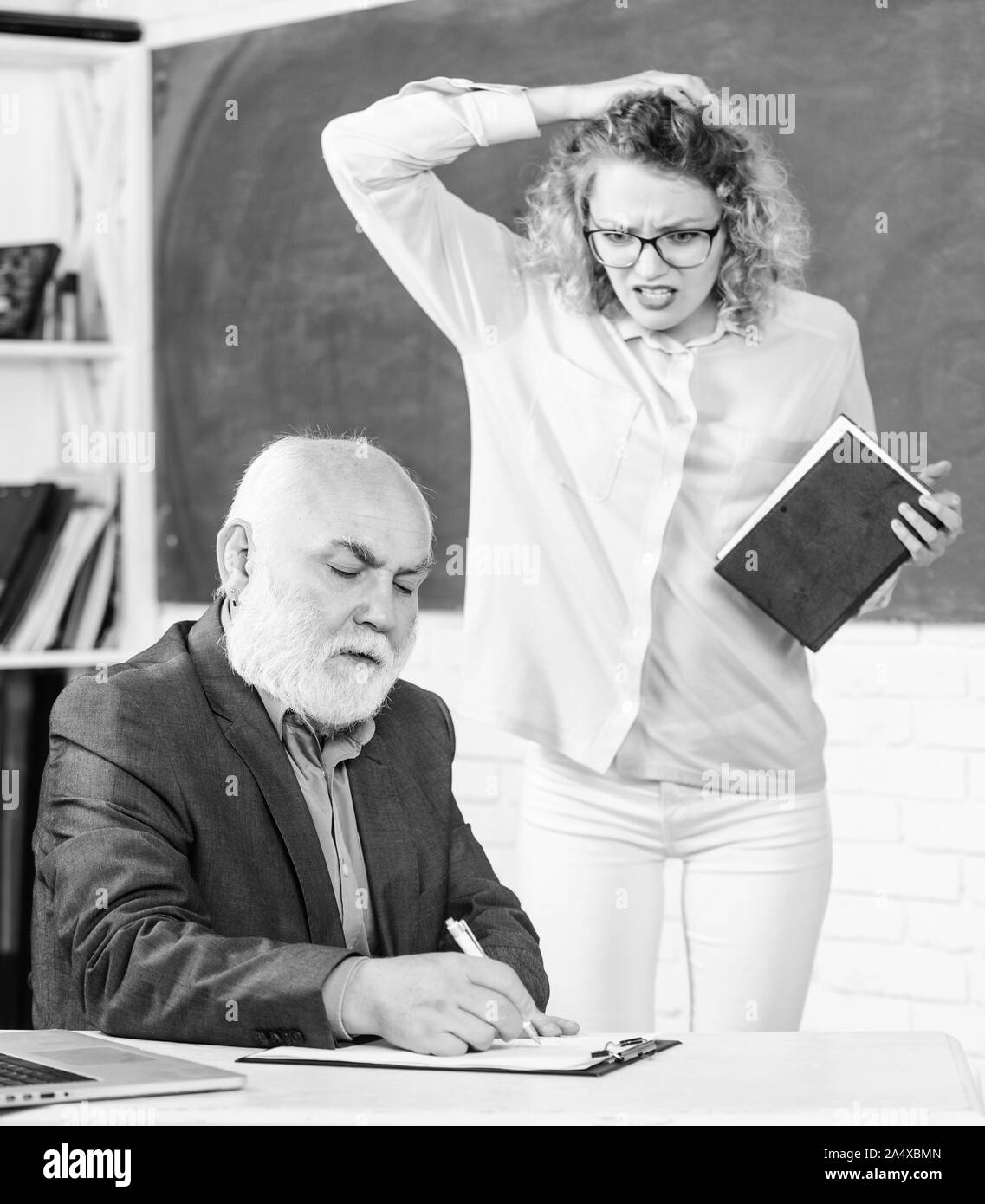 In nessun modo docente senior e la donna a scuola lezione. studente ragazza con il tutor man a Lavagna. studente e tutor con laptop. passa all'esame. Sala insegnanti. Ottenere informazioni per la lezione a scuola. Foto Stock