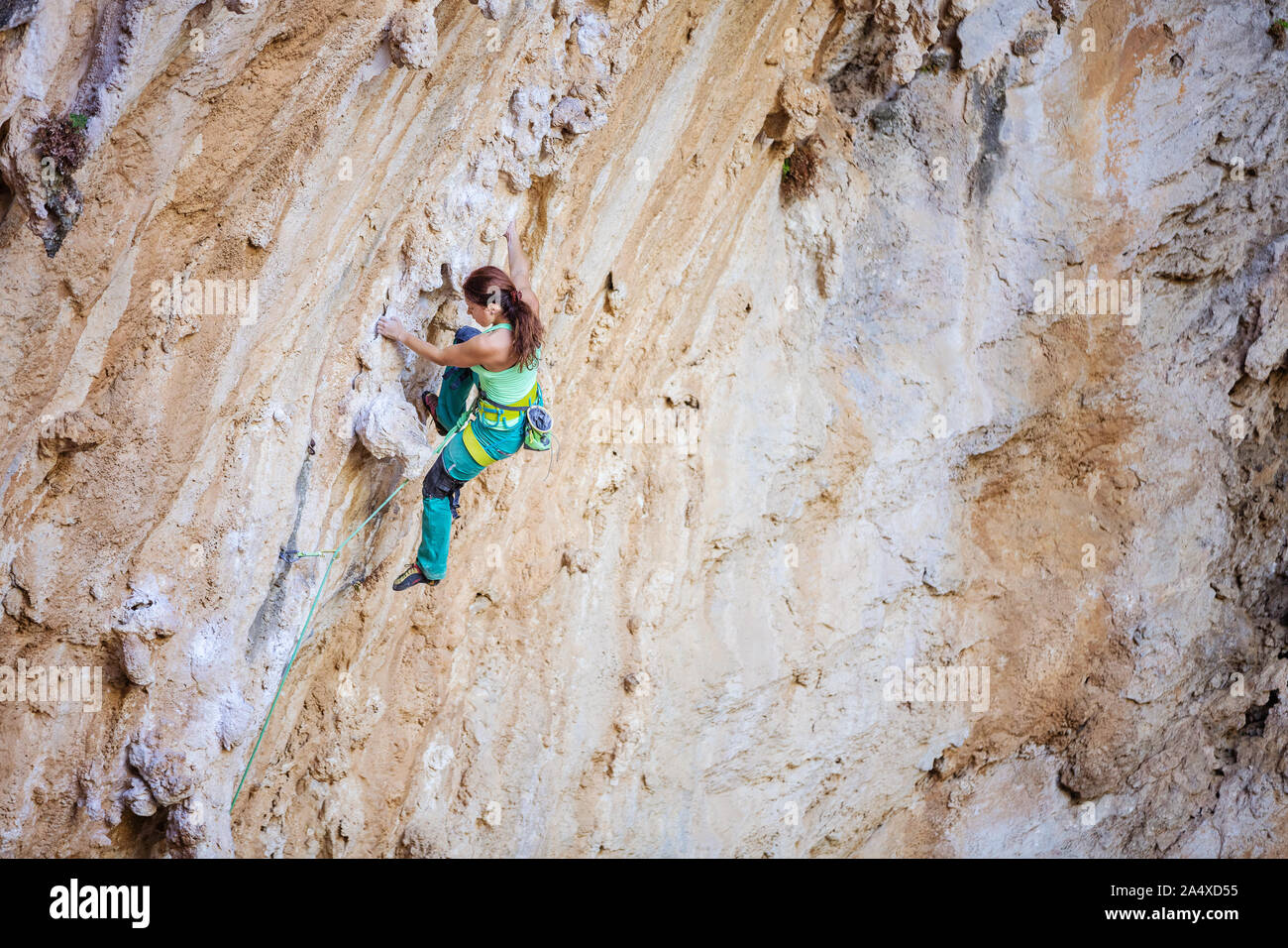 Giovane donna climbing impegnativo percorso sulla rupe a strapiombo Foto Stock