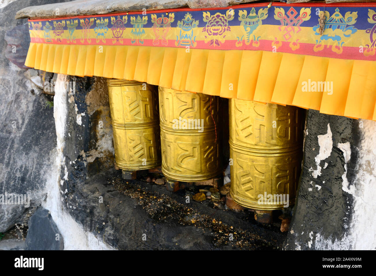 Golden ruote della preghiera al monastero di Drepung attendere un adoratore di Bhuddhism tibetano a girare una preghiera per l'universo. Foto Stock