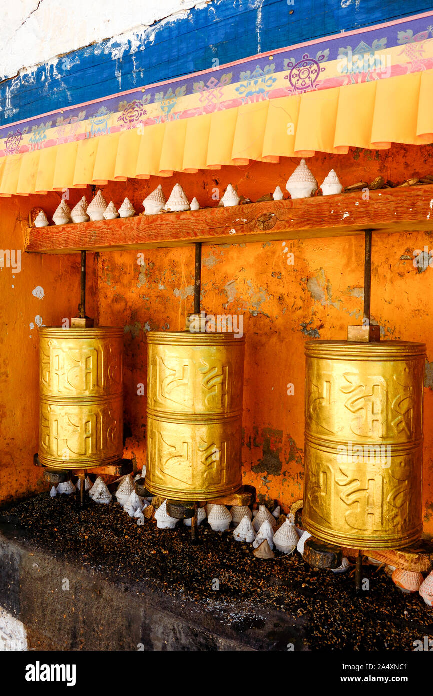 Golden ruote della preghiera al monastero di Drepung attendere un adoratore di Bhuddhism tibetano a girare una preghiera per l'universo. Foto Stock