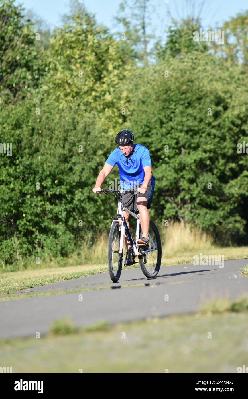 Maschio adulto atleta e la solitudine che indossa il casco in Bicicletta Equitazione Foto Stock