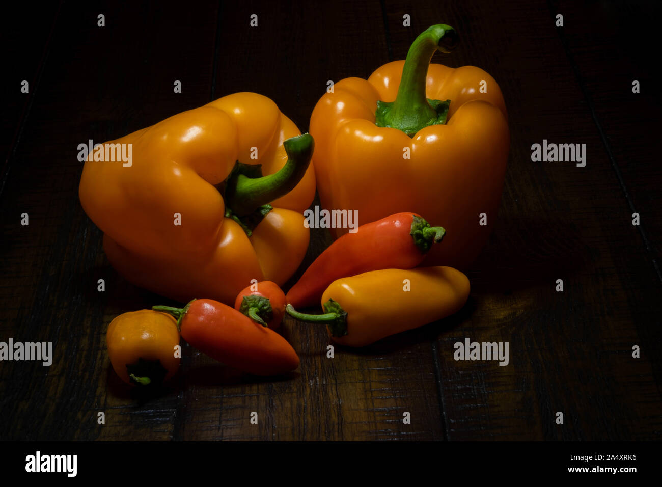 Ancora vita immagine di arancio e il rosso dei peperoni dolci con uno sfondo scuro. Foto Stock