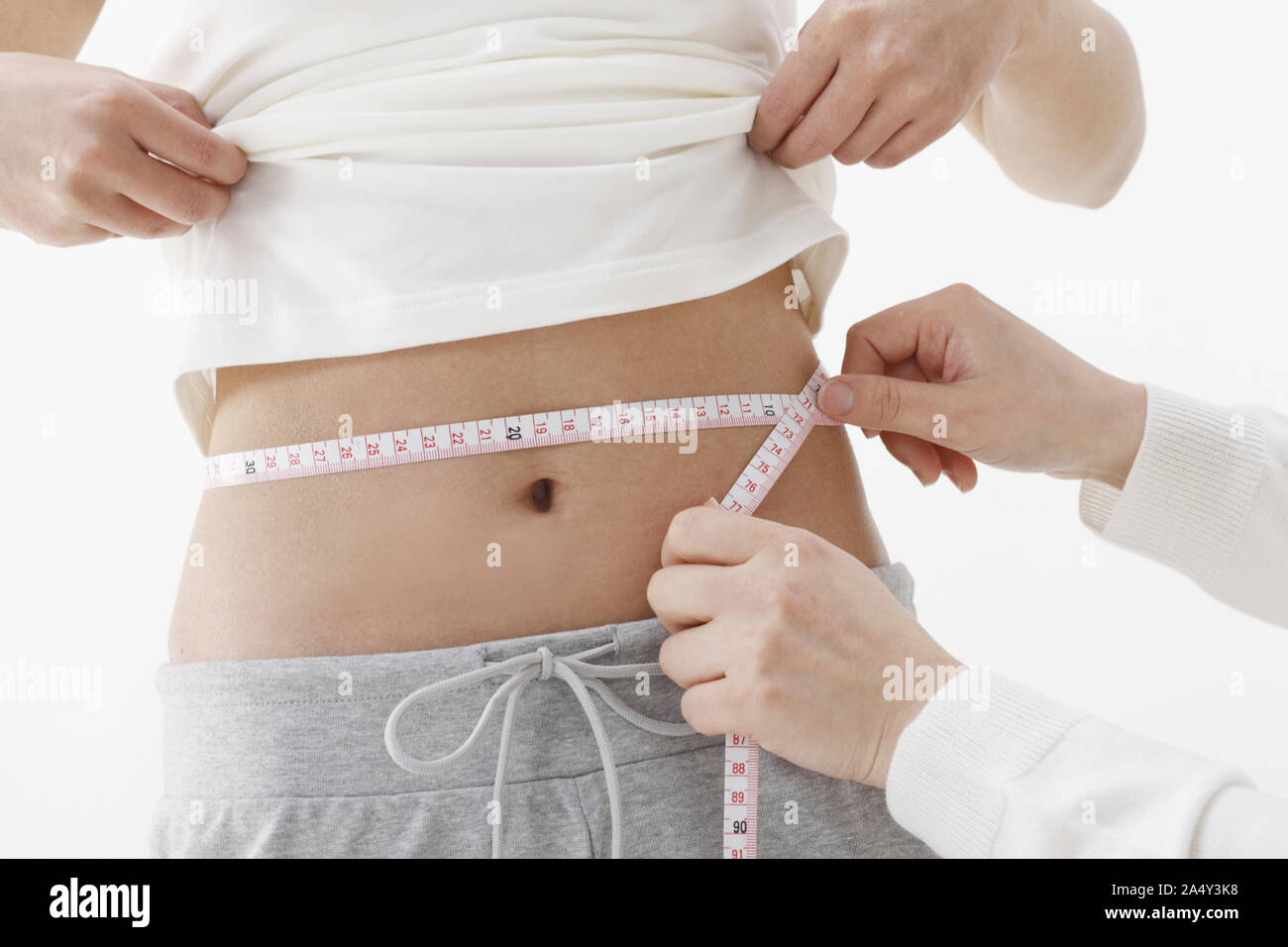 Un molto montare donna asiatica misurando la sua vita Foto Stock