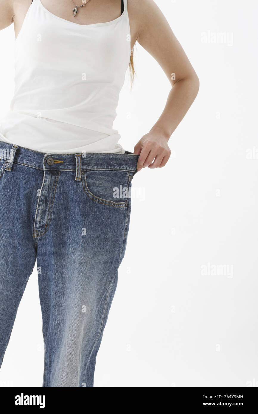 Un felice perdita di peso di sostegno femmina jeans larghi isolati su sfondo bianco Foto Stock