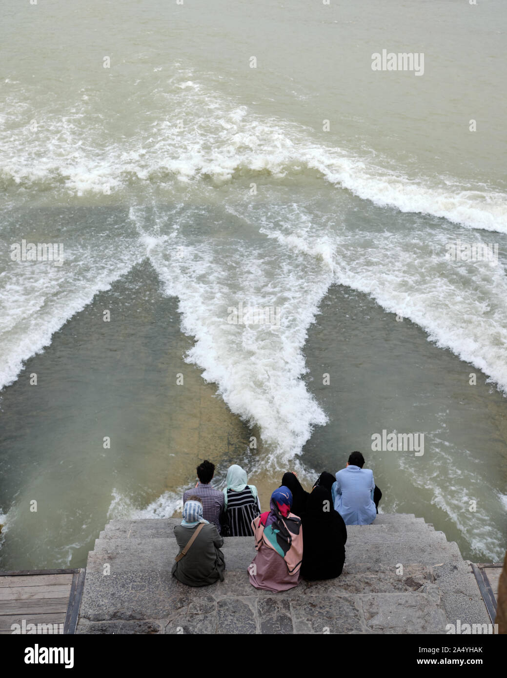 Isfahan, Iran - 1 Maggio 2019: Gente seduta sul ponte Khaju guardando l'evento inconsueto di acqua che scorre sotto il ponte Foto Stock