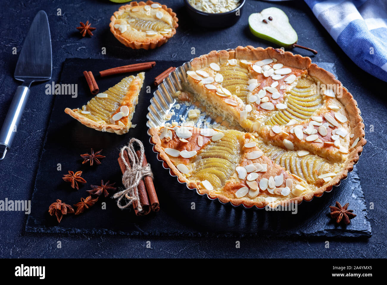 Close-up della classica francese Crostata di pere, la Tarte Bourdaloue riempito con pere in camicia e frangipane crema servita su una pietra nera di bordo su un calcestruzzo t Foto Stock