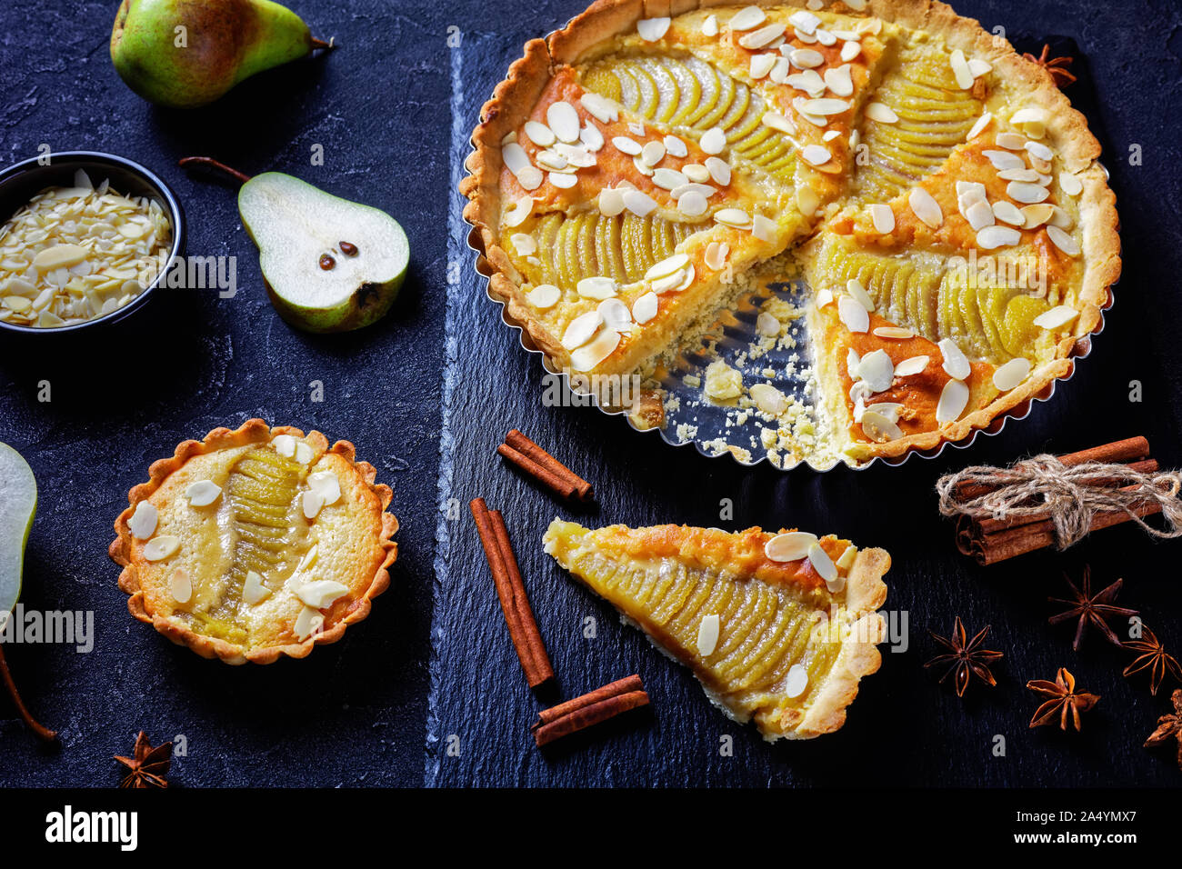 Francese Crostata di pere, la Tarte Bourdaloue riempito con pere in camicia e frangipane crema servita su una pietra nera di bordo su un tavolo in cemento, orizzontale vie Foto Stock