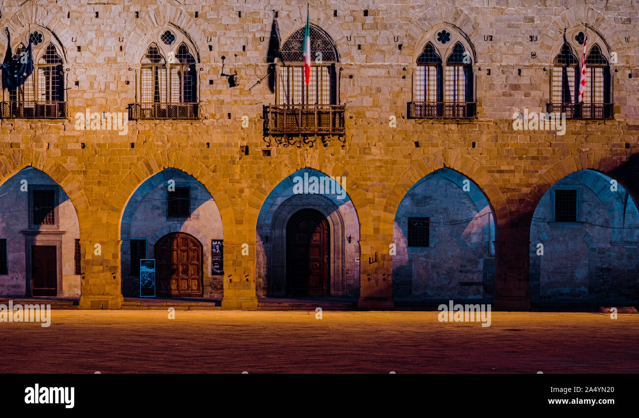 La bella facciata frontale di Pistoia medievale palazzo in pietra in Piazza Duomo di notte con la bandiera italiana e la famiglia Medici crest Foto Stock