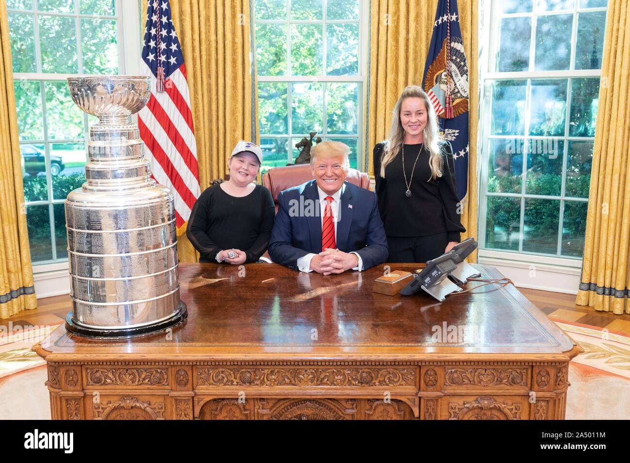 U.S presidente Donald Trump, centro, pone con St Louis Blues super fan Laila Anderson, sinistra e e sua mamma Heather, a destra a fianco della Stanley Cup Trofeo campionato all Ufficio Ovale della Casa Bianca Ottobre 15, 2019 a Washington, DC. Foto Stock